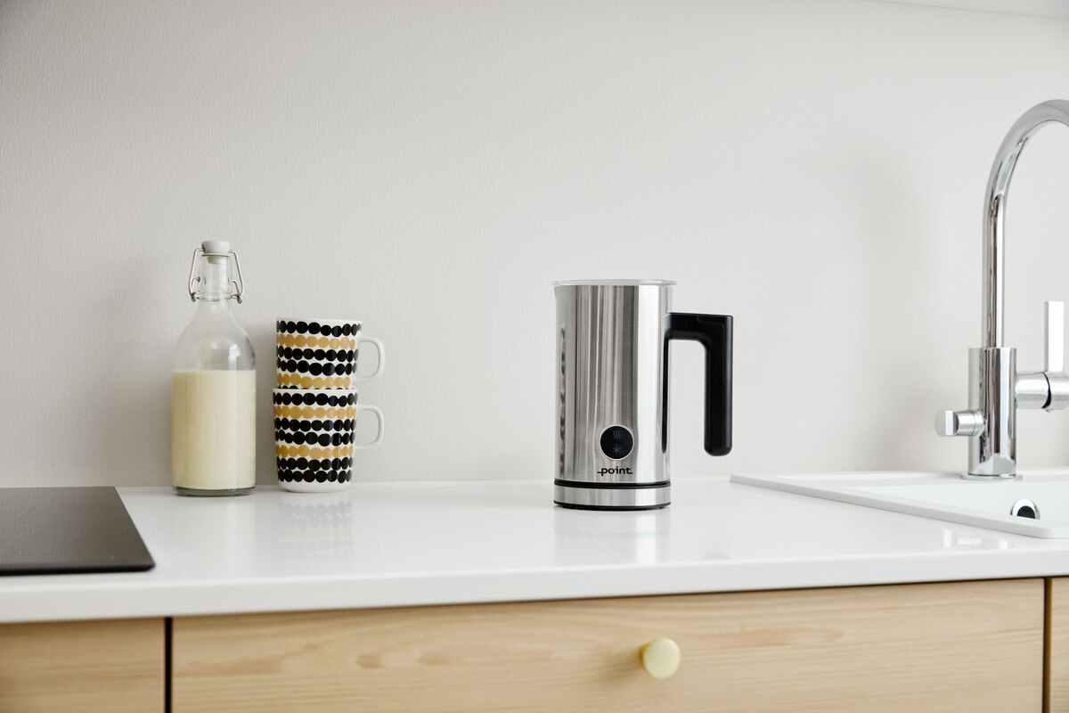 POINT POMF17SS milk frother on a white kitchen worktop next to a glass jar of milk and some black and yellow pattrened coffee mugs