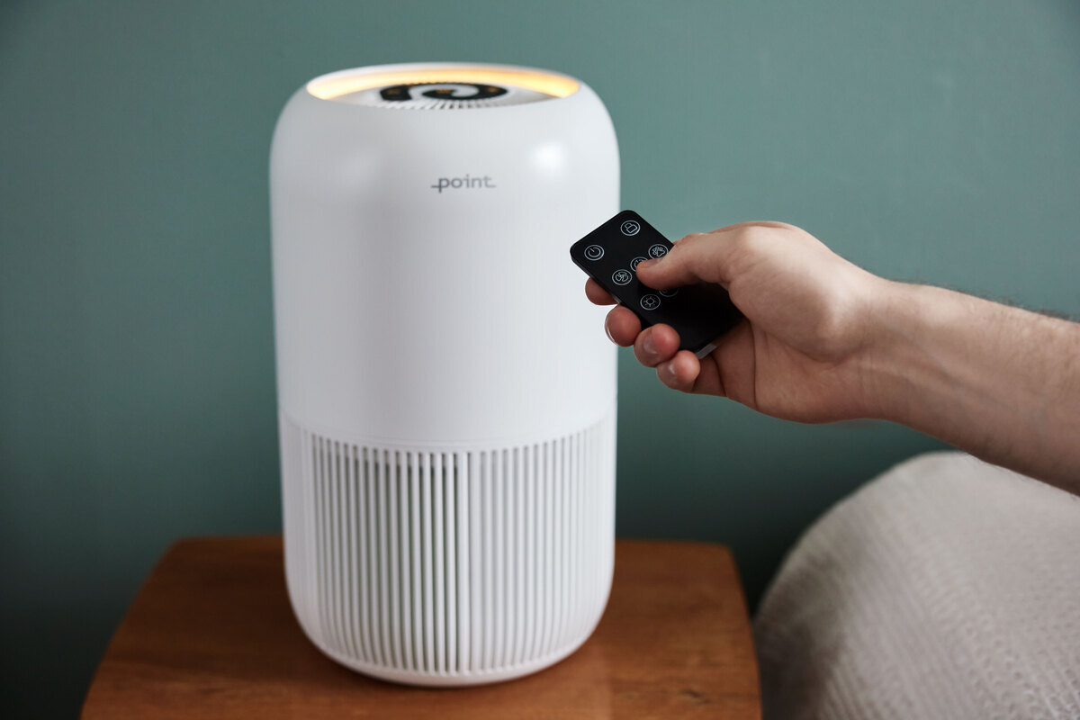 Person adjusting the air purifier with a remote control