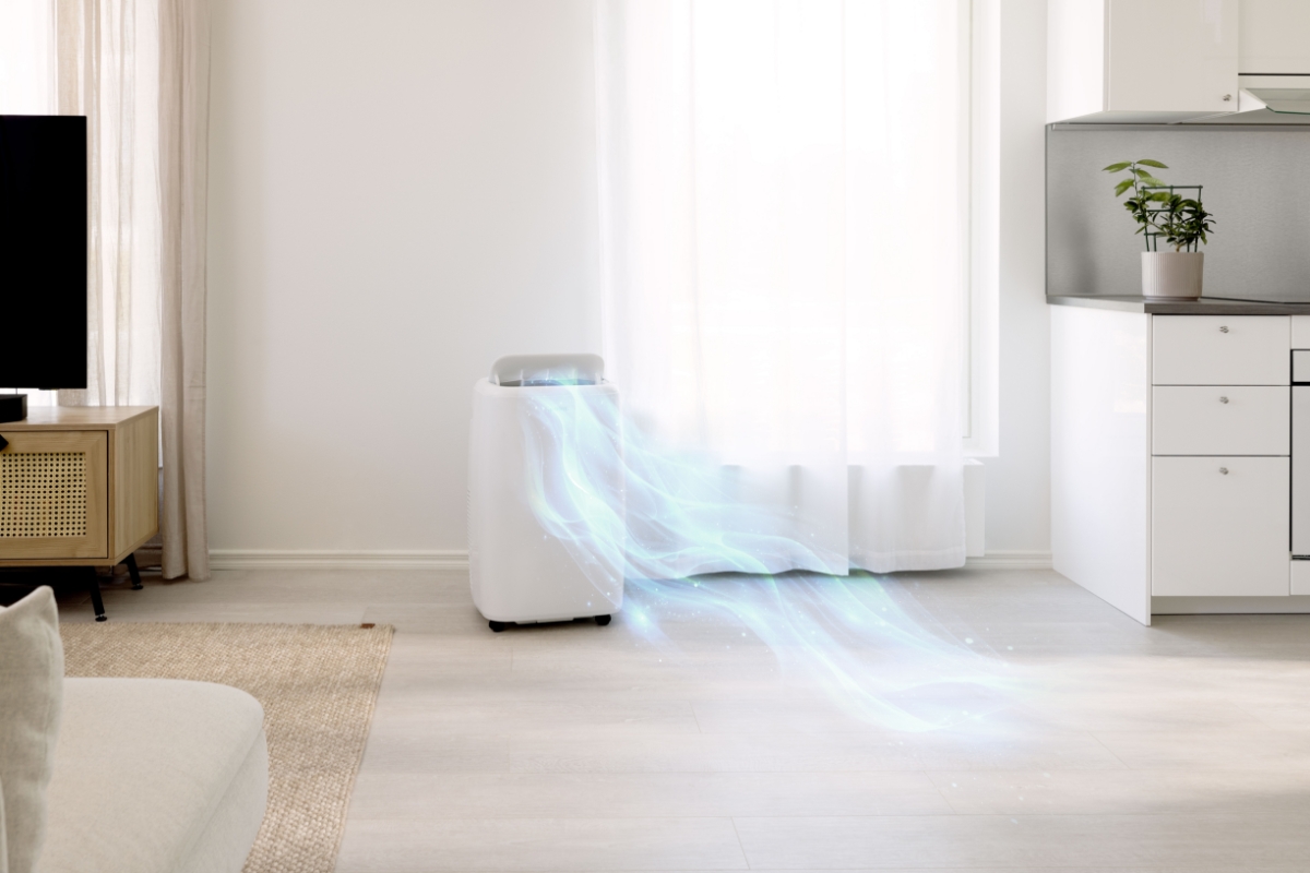 A white Point air conditioner on a light wooden floor in a living room next to a big window with lots of light and white curtains and blue flow blowing out of the device expressing the air flow of the device