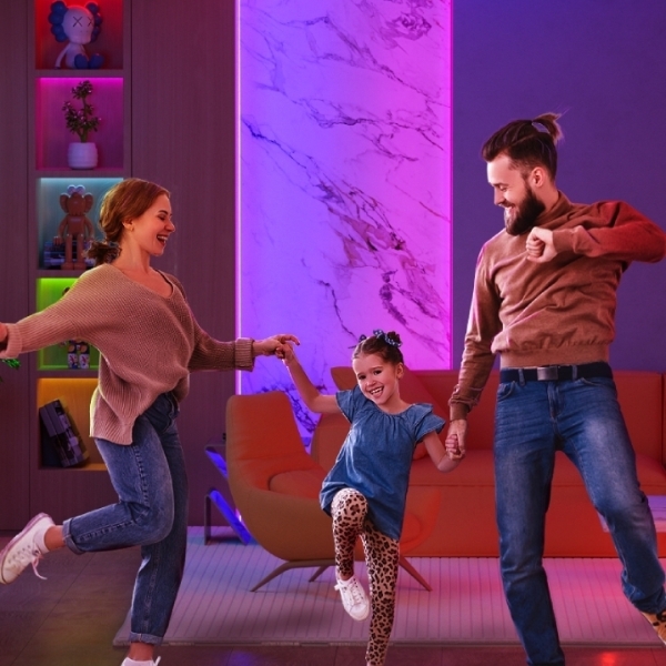 A mother, daughter and father dancing in a living room with purple lights