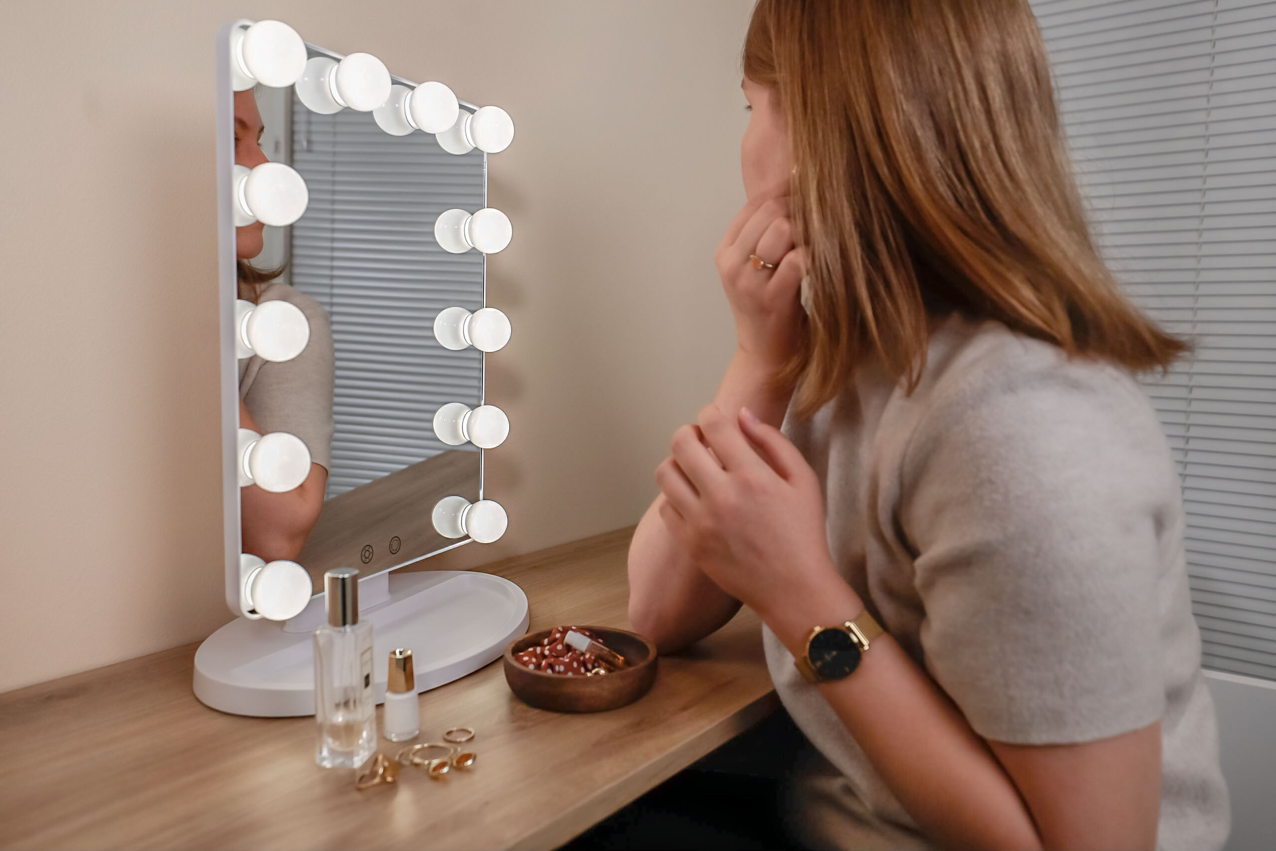 Woman attaching earrings in front of the makeup mirror