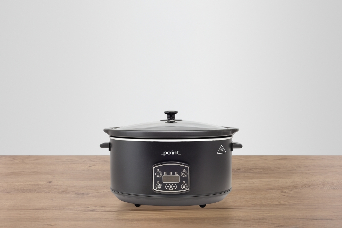 A black Point slow cooker on a wooden table with light grey background with no accessories