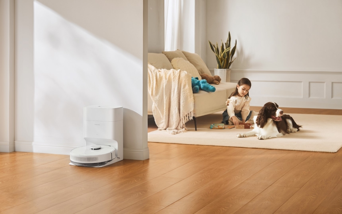 DREAME D10 PLUS GEN2 ROBOT VACUUM WH parked in its dock while a child and dog play on the background